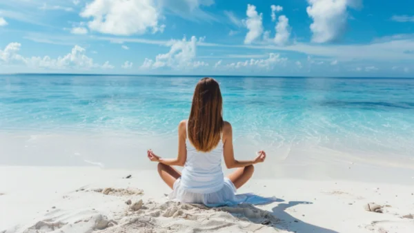 Woman enjoying 10 minutes of self care meditating on a beach.