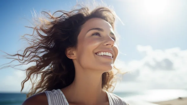 A happy woman smiling while walking on a beach.